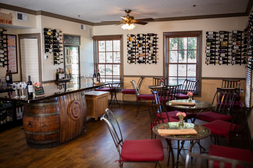 A cozy wine bar featuring wooden decor, a circular counter, and rows of wine bottles on the walls.
