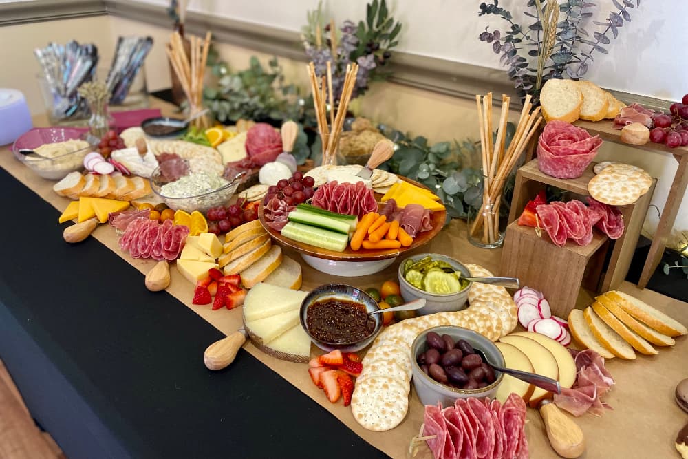 A colorful spread of cheeses, cured meats, fruits, and crackers arranged on a table.