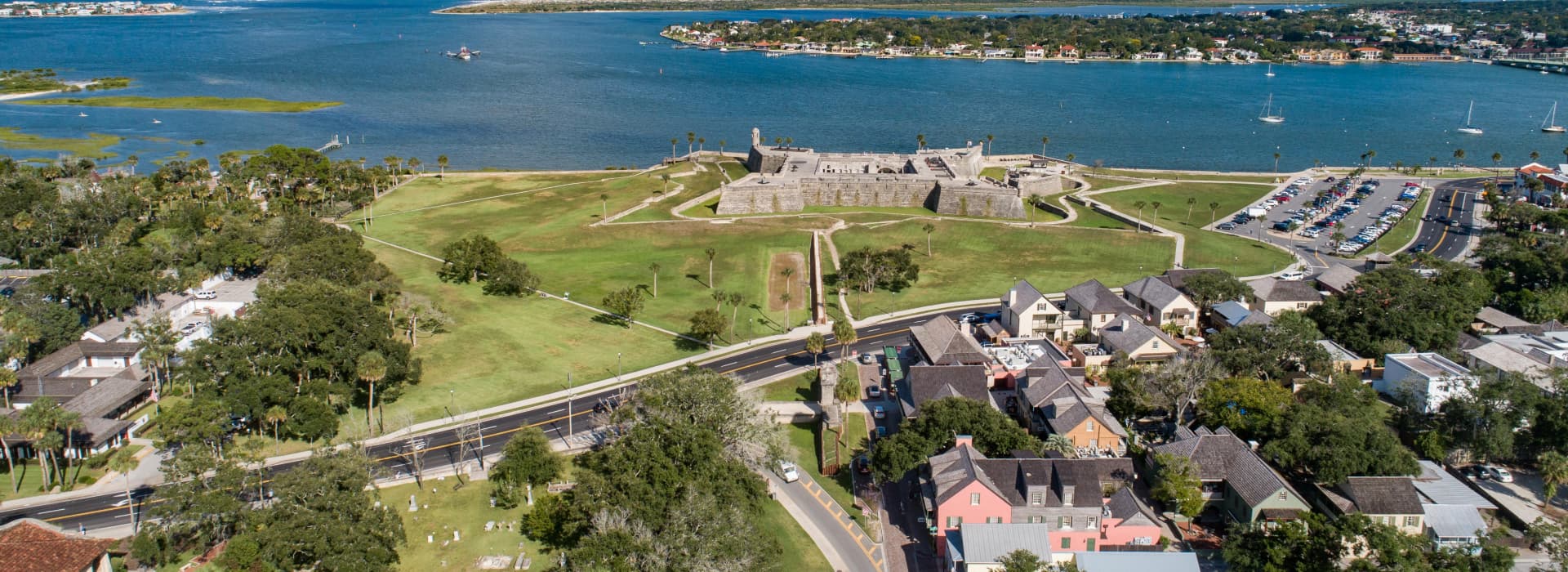 Aerial view of a historic fort surrounded by greenery and water, with adjacent roads and buildings.